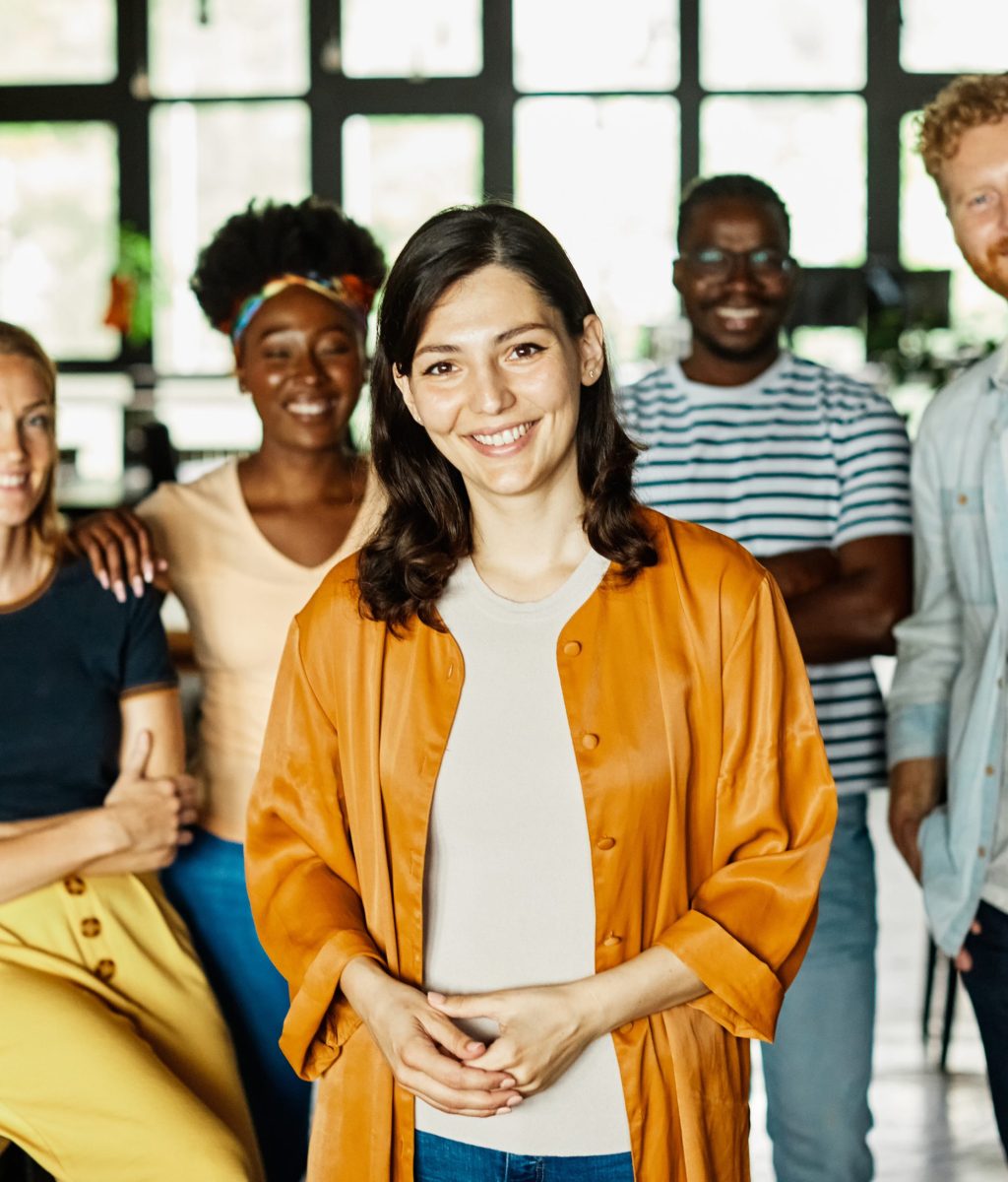 Group of young business people having a meeting or presentation and posing in the office. Portrait of a young business woman and a group of young businesspeople. Startup concept